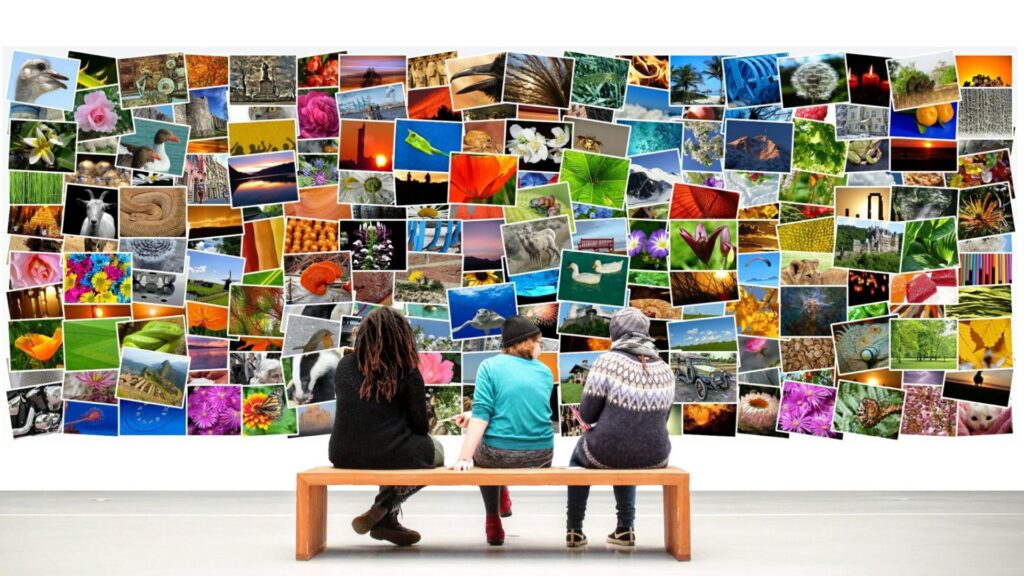 Três pessoas sentadas em um banco observando uma vasta parede de imagens diversas, destacando a importância dos detalhes visuais em conteúdo digital.
