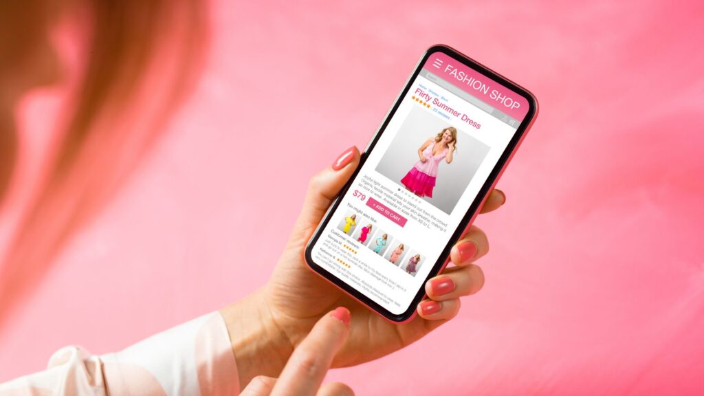 Mão feminina segurando um smartphone com uma página de e-commerce exibindo um vestido de verão, destacando a importância de uma experiência de compra otimizada para dispositivos móveis.